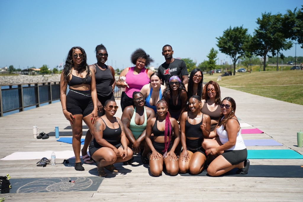 Outdoor group class posing together on a boardwalk with yoga mats