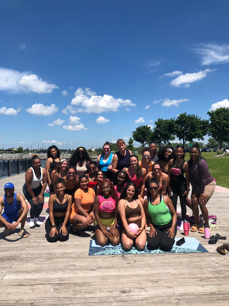 Large outdoor community fitness group posing on a boardwalk