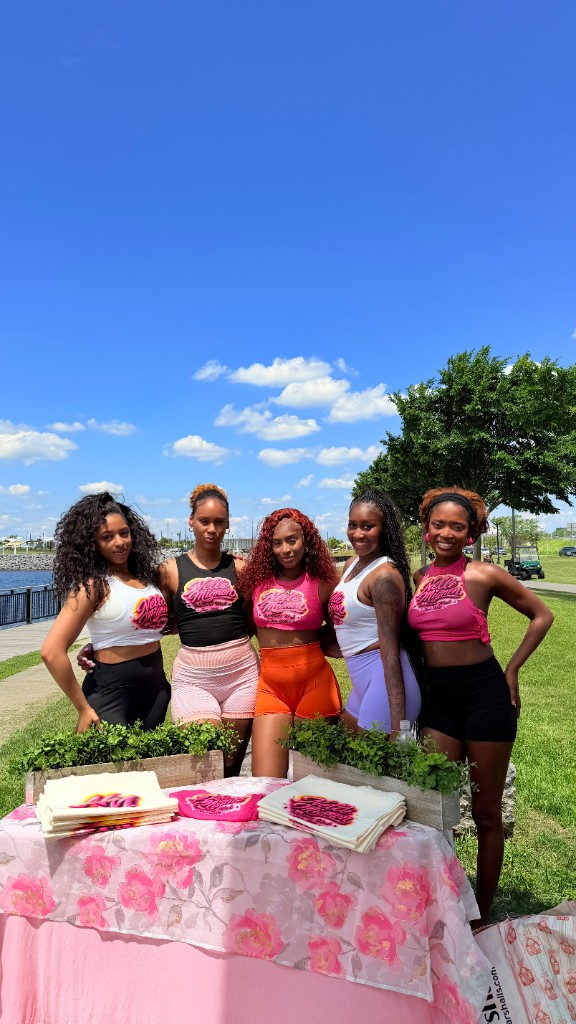 Nellé Mignon team at a Wellness Week merch table outdoors