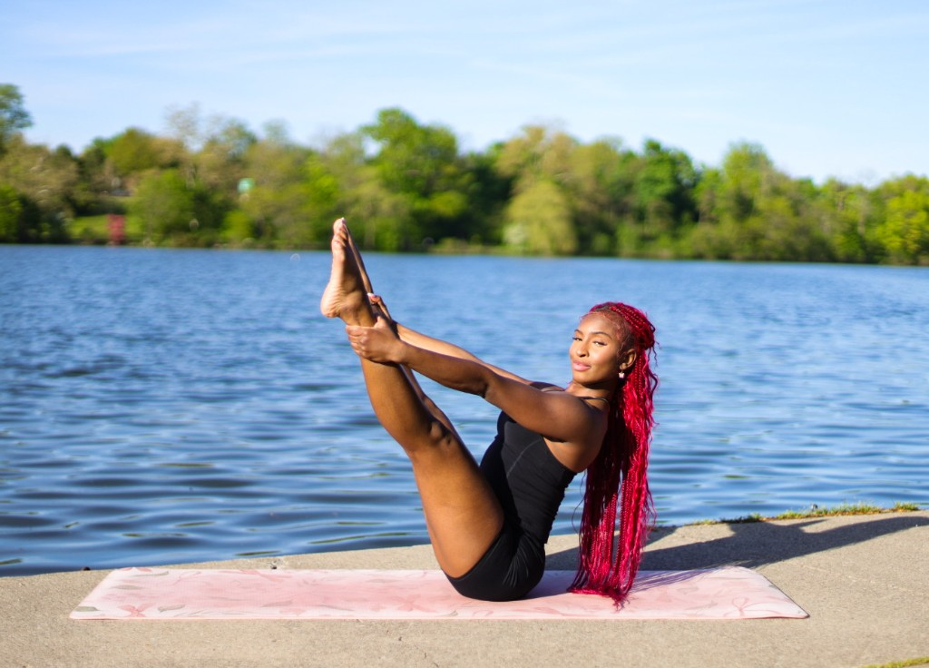 Nellé Mignon balanced in a V-sit pose outdoors by the lake
